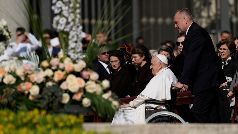 Papst Franziskus (2.v.r) kommt in einem Rollstuhl auf dem Petersplatz im Vatikan an.