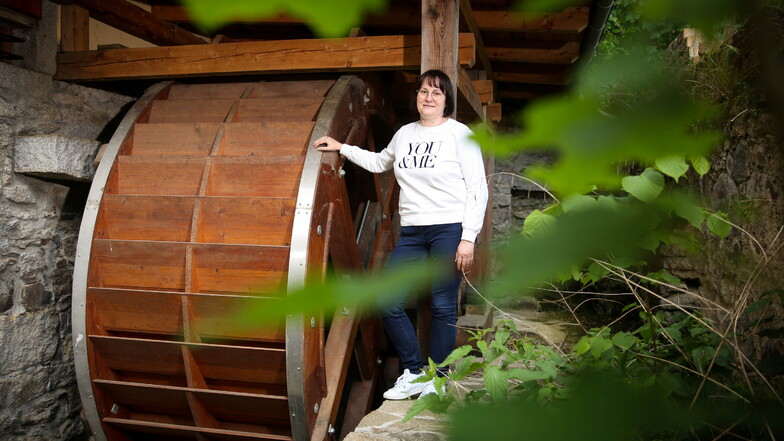 Ilka Zessin an dem sanierten hölzernen Mühlrad der Hainmühle in Elstra. Mit ihrem Lebensgefährten hat sie vor 15 Jahren die Mühle gekauft. Am Pfingstmontag sind Besucher willkommen.