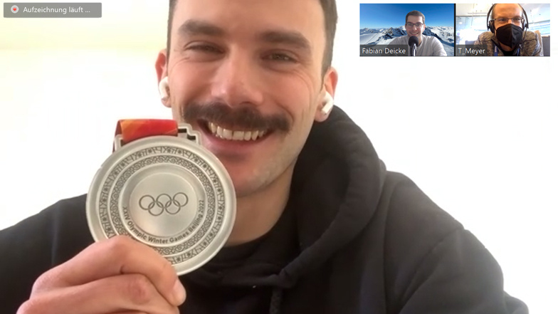 Der Dresdner Skeletoni Axel Jungk zeigt in der Videoschalte bei der Aufnahme des Podcasts "Dreierbob" seine Silbermedaille.