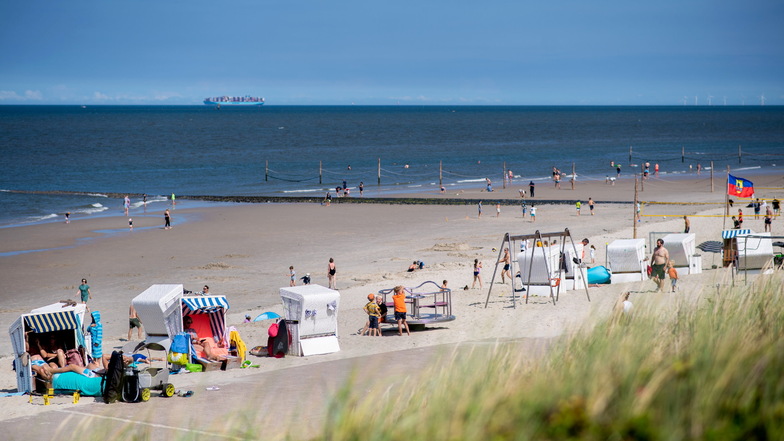 Zahlreiche Touristen sitzen bei sonnigem Wetter in Strandkörben am Strand der Insel Wangerooge.
