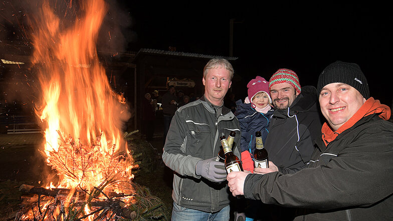 Ein Prost auf die Gemeinschaft: Ingi Wieczorik, Stefan Kowalski mit der kleinen Heidi und Jörg Merzdorf stehen am Feuer in Beicha.