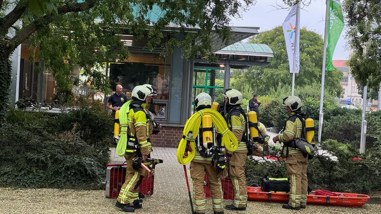 Feuerwehrleute stehen voll ausgerüstet am Donnerstagvormittag vor dem Haus der Presse in Dresden.