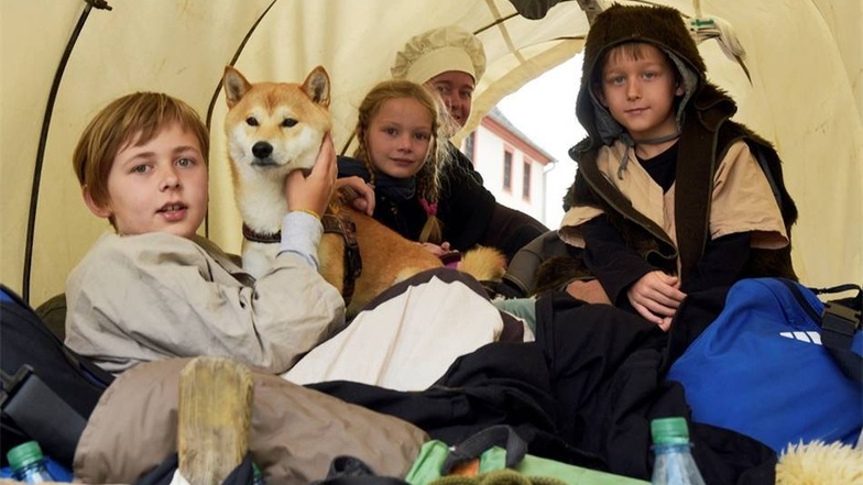 Damit die Kinder nicht vollkommen erschöpft im Lager ankommen, ist für sie ein Platz im Planwagen reserviert. Dort haben es die kleinen Siedler gemütlich. Sie sitzen auf weichen Decken.