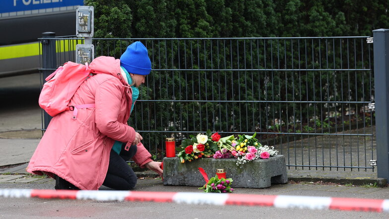 Eine Frau legt vor dem Gebäude der Zeugen Jehovas in Hamburg Blumen nieder. Bei einem Amoklauf sind am Donnerstagabend mehrere Menschen getötet worden.