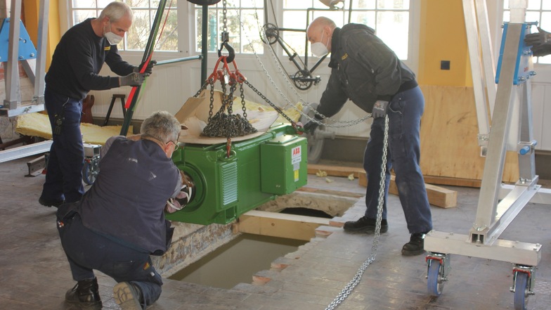 Durch ein Loch in der Decke der Bergstation wird der generalüberholte Motor in das Maschinenhaus abgelassen. Wegen ihrer genauen Ortskenntnis erledigen das die DVB-Bergbahnmitarbeiter selbst. Auf seinem Platz verankert, soll der Motor die historische Dres