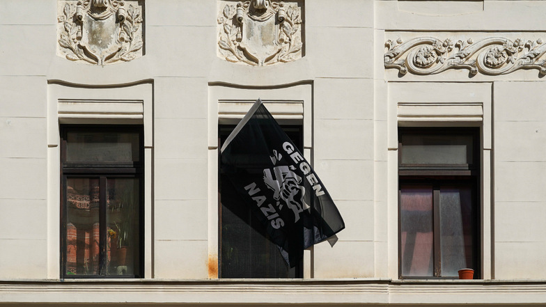 Eine Fahne mit der Aufschrift „Gegen Nazis“ hängt aus einem Fenster.