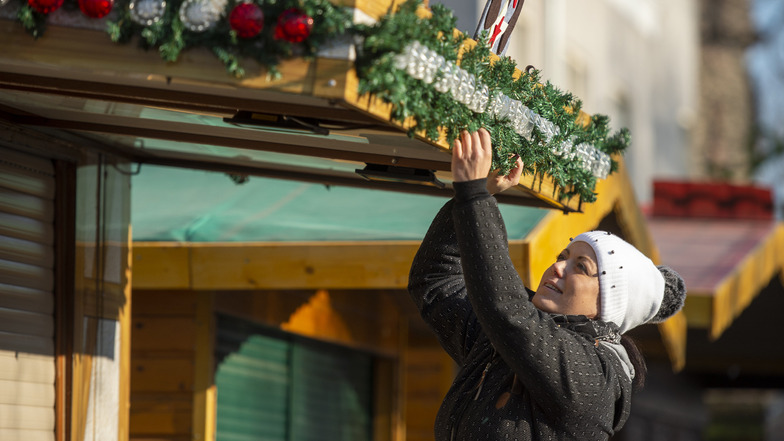 Elisa Berndt schmückt eine der Buden auf dem Coswiger Weihnachtsmarkt. Am Freitag öffnet der Markt um 13 Uhr. In Weinböhla geht es eine Stunde später los.