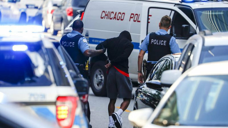 Polizeibeamte halten einen Mann auf der Straße in Chicago fest und führen ihn ab.