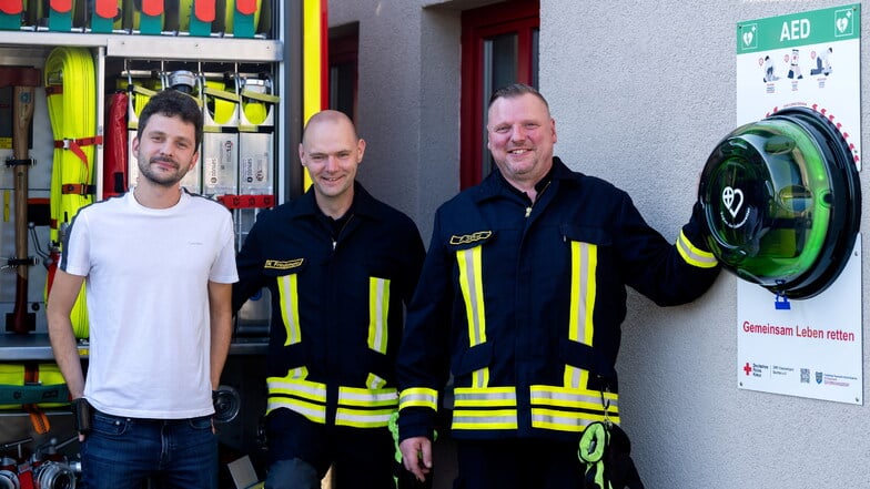 Freude bei Carsten Herkner, Michael Friedmann und Ortswehrleiter Peter Sicker (v.l.): Am Feuerwehrgerätehaus in Geißmannsdorf gibt es jetzt einen öffentlichen Defibrillator. Er ist Teil der Lebensretter-Region Ostsachsen.