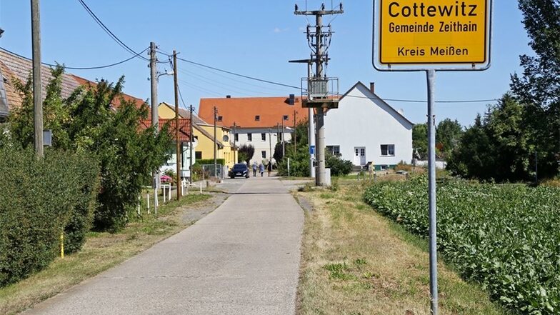 Eine schmale Betonpiste führt zwischen den Feldern der Agrargenossenschaft Kreinitz nach Cottewitz. Der Elberadweg auf dem Deich macht einen Bogen rings um das Dorf.