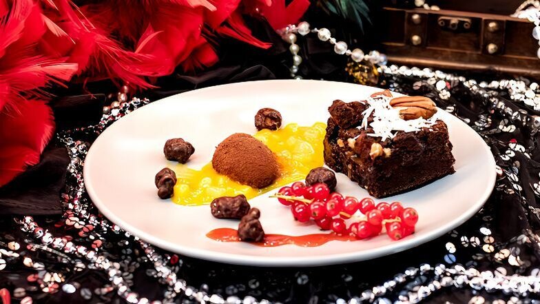 Süßes Finale mit "Schokolade trifft Mango": Ein Schokoladen-Brownie, begleitet von einem fruchtigen Kompott aus Mango, Ananas und Passionsfrucht. Die geeiste Mango im Schokoladenmantel wird von einem verlockenden Erdbeercoulis und Schoko-Karamell-Popcorn 
