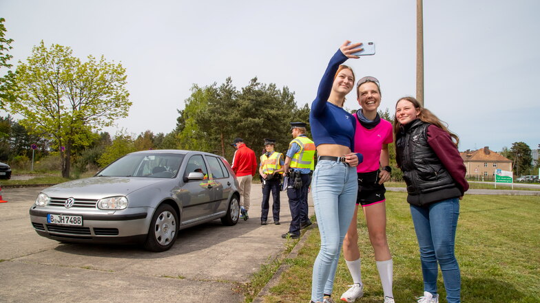 Während ihr Freund Sven Polizisten sein Fahrzeug zur Kontrolle zeigt, hat Joyce Selfie-Spaß mit zwei Rothenburger Oberschülerinnen. Sie haben die Marathonläuferin aus dem Internet erkannt.