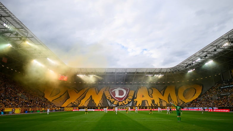 Dynamos Fans im K-Block zeigen eine Blockfahne und zünden Pyrotechnik.