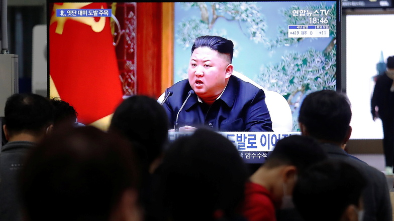 Menschen schauen auf einen Bildschirm im Bahnhof Suseo, auf dem ein Bild des nordkoreanischen Machthabers Kim Jong Un während einer Nachrichtensendung gezeigt wird.