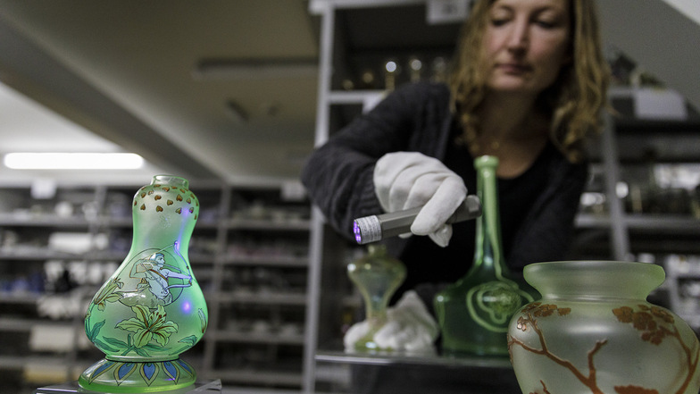 Manches Glas leuchtet unter UV-Licht durch seine bestimmte Zusammensetzung. SZ-Redakteurin Ines Eifler probiert das im Depot des Schlesischen Museums aus.