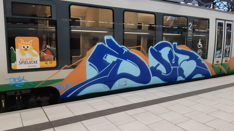 Mit hell- und dunkelblauer sowie orangener Farbe haben Unbekannte einen Zug besprüht, der auf dem Gelände des Bischofswerdaer Bahnhofs stand.