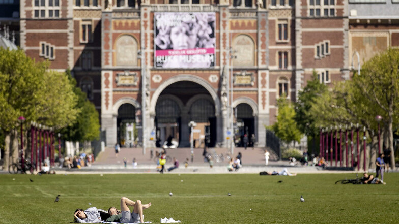 Auf dem Rasen von Museumplein in Amsterdam liegen Menschen.Ein Niederlande-Besuch wird im Sommer wohl möglich sein.