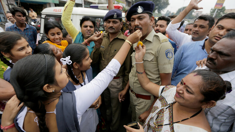 Indische Frauen bieten Polizisten Süßigkeiten an zur Feier der vier toten mutmaßlichen Vergewaltiger.