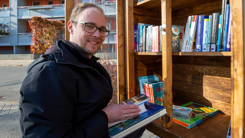 Heute mal als Bibliothekar: Stadtteilmanager Lutz Michen beim Einräumen des Mügelner Bücherschrankes.
