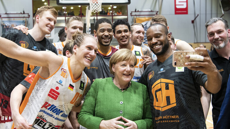 Virgil Matthews (2.v.r) von den Chemnitzer Niners macht mit Bundeskanzlerin Angela Merkel (CDU) bei einem Besuch des Basketballspiels der Chemnitzer Niners gegen Ehingen Urspring ein Selfie.
