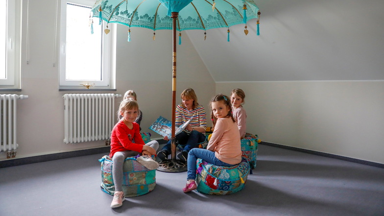 In einem Raum ist eine Leseecke eingerichtet. Xara und Julia (vorn) sowie Elena und Tilda (hinten) - alle fünf Jahre alt - lauschen Kindererzieherin Annette Kanis.
