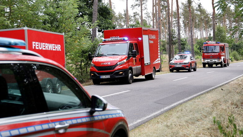 Mehrere Einsatzfahrzeuge der Feuerwehr stehen an einer Straße am Rande der Gohrischheide. Zeitweise waren auf sächsischer Seite bis zu 200 Feuerwehrleute im Einsatz. Dieses Großaufgebot könnte jetzt für eine große Rechnung sorgen.