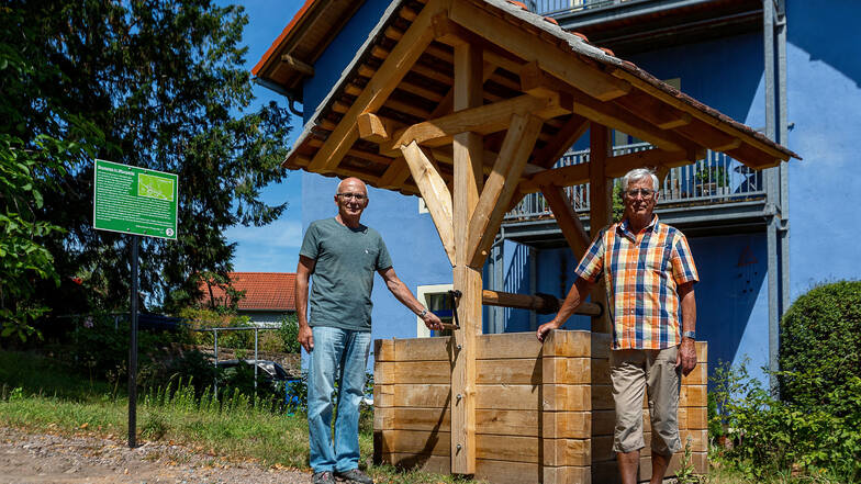 Eberhard Wätzig (links) und Peter Kretzschmar stehen an einem Brunnen in Wurgwitz, dessen Sanierung der Heimatverein organisiert hat.