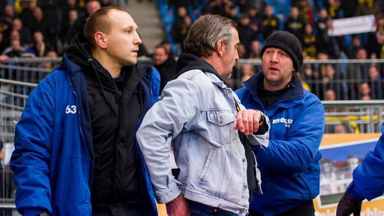 2016 wird Dynamos Sportchef Ralf Minge im Innenraum des Magdeburger Stadions von Ordnern festgehalten, als er deeskalieren will.