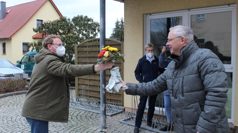 Gemeindewahlleiter Holger Koßwig (rechts) gratuliert dem künftigen Zeithainer Bürgermeister Mirko Pollmer (links) mit Blumen und dem in der Pandemie gebührenden Abstand.