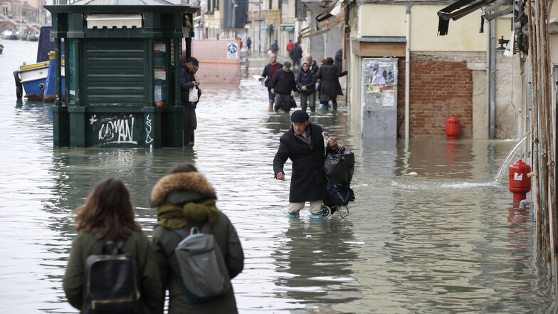 Menschen waten durch eine überflutete Straße.