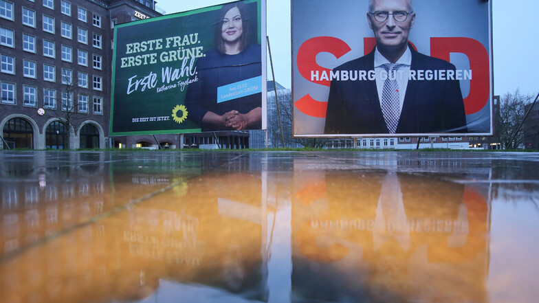 Ein Wahlplakat, das am Wahlsonntag Katharina Fegebank (Grüne) zeigt, steht bei Regen neben einem Plakat, das Peter Tschentscher (SPD). Die beiden Parteien wollen zusammen regieren.
