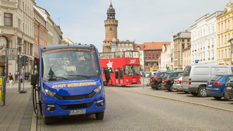 In Görlitz bieten verschiedene Unternehmen Stadtrundfahrten mit Bussen an. Zum Beispiel konkurrieren der Stadtschleicher (blaues Fahrzeug) und der Görliwood-Bus (rot).