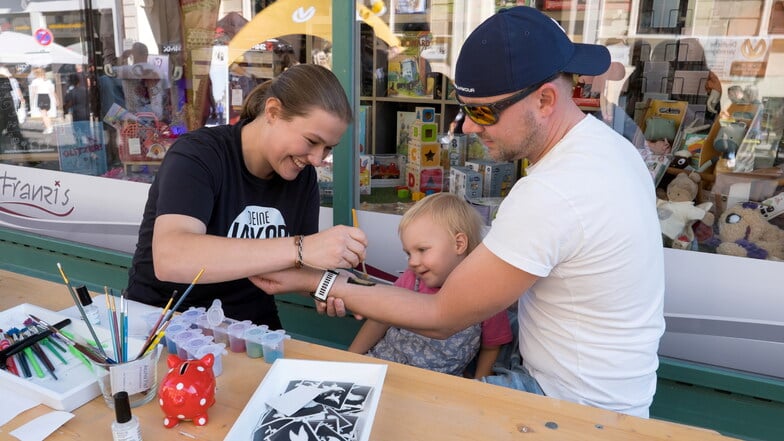 Christian mit Tochter Mara (2 Jahre) bekommt von Rieke Lüers ein Glitzer-Tattoo auf der Jakobstraße verpasst.