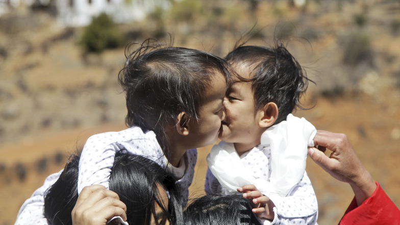 Die 2018 getrennten bhutanischen siamesischen Zwillinge Nima und Dawa auf den Schultern ihrer Mutter und ihrer älteren Schwester.