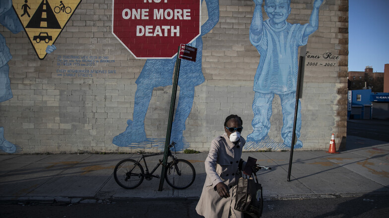 Eine Frau mit einer Mundschutzmaske überquert eine aufgrund der Ausgangsbeschränkungen leere Straße im New Yorker Stadtteil Brooklyn. 