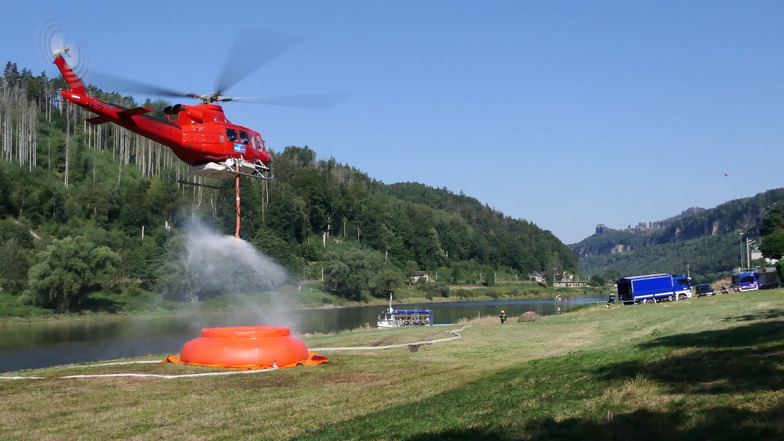Ein Hubschrauber beim Wasserfassen an der Elbe: Das THW stellt die Löschwasserbehälter bereit.