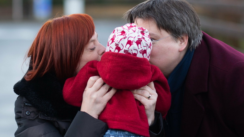 Gesa Teichert-Akkermann (l) und Verena Akkermann geben ihrer Tochter Paula (11 Monate alt) ein Küsschen auf die Wange. Familie Akkermann will über Familiengerichte eine Gleichstellung mit heterosexuellen Paaren bei der Elternschaft erreichen.