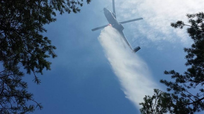 In der Nähe der Affensteine in Bad Schandau wütet seit Montagabend ein Waldbrand. Ein Hubschrauber löscht.