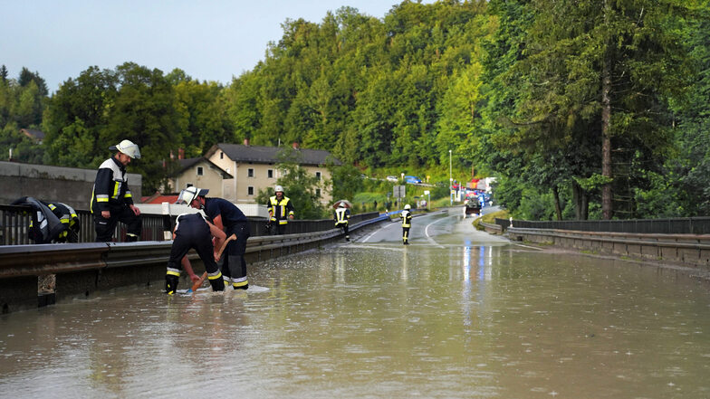 Nach starken Regenfällen ist eine Straße überflutet. Zahlreiche
Straßen im Landkreis Miesbach in Bayern waren unpassierbar und mussten durch die Feuerwehr
gesperrt werden.