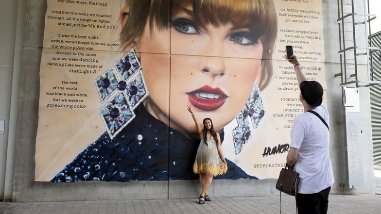 Eine junge Frau posiert in London  vor einem großen Wandgemälde von US-Popstar Taylor Swift am Wembley-Stadion. Die britische Hauptstadt bleibt trotz der kürzlichen Terrorgefahr in Wien entspannt.