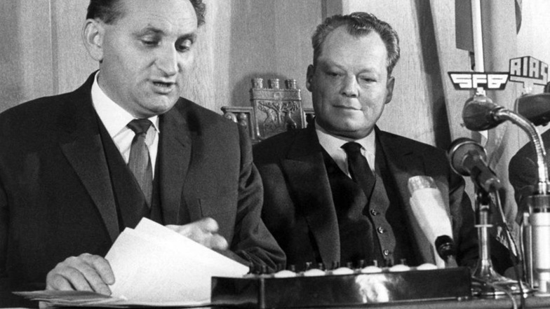 Willy Brandt und Senatspressechef Egon Bahr (rechts) erläutern am 17. Dezmber 1963 auf einer Pressekonferenz im Rathaus Schöneberg die mit Vertretern der Sowjetzone getroffene Regelung in der Passierscheinfrage.