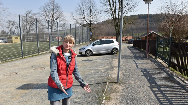 Schulleiterin Simone Petters zeigt auf die kaum wahrnehmbare Steinkante, die den Schulweg in Obercarsdorf vom Parkplatz abgrenzen soll.