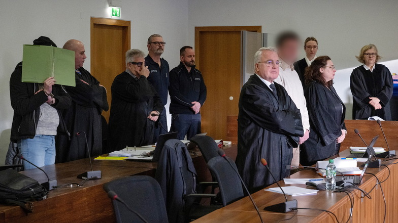 Die beiden Angeklagten (l und 4.v.r) stehen vor Beginn der Hauptverhandlung im Gerichtssaal 8 des Potsdamer Landgerichts neben ihren Anwälten.