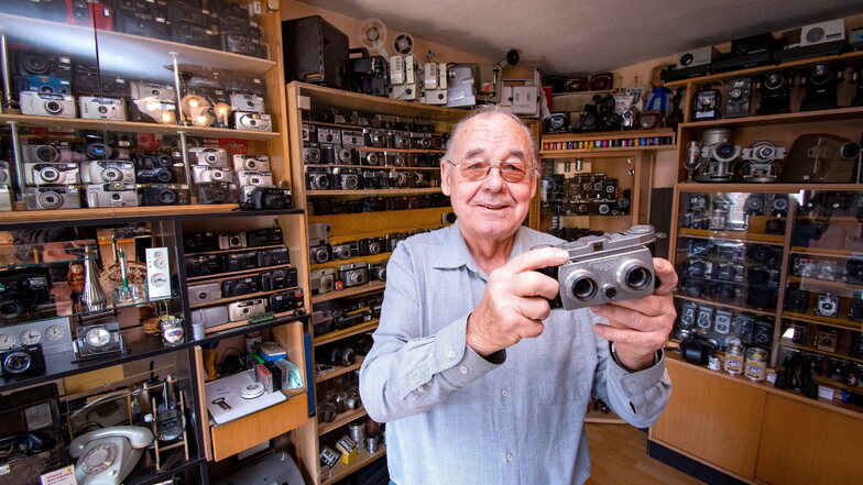 Alfred Kruggel steht in seiner Kamerasammlung. Er hat einen ganzen Raum mit Vitrinen und Hunderten Kameras gefüllt. In der Hand hält er eine Belplasca-Stereokamera, die in Dresden hergestellt wird.