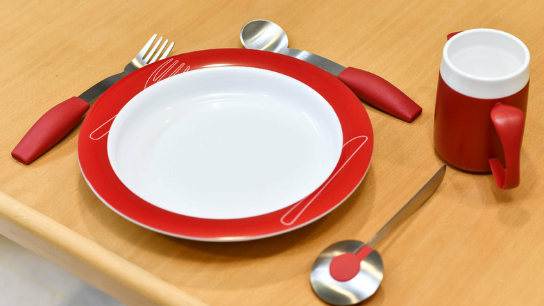 Dickere Griffe am Besteck und an der Tasse und ein erhöhter Tellerrand erleichtern das Essen. 