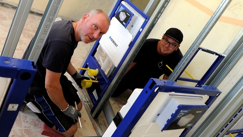 Jörg Schiemann und Steven Burghardt wechseln in den Toiletten Module und Leitungen aus.