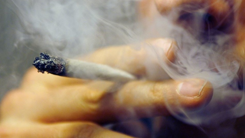 Ein Mann raucht einen Joint mit Marihuana. Um über die Risiken des Konsums von Tabak, Alkohol und illegalen Drogen aufzuklären, setzt die Polizeidirektion Dresden auf Präventionsangebote wie Schulprojekte und Elternabende. Foto: Daniel Karmann/dpa