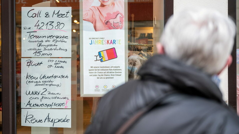 Ein Kunde betrachtet die Einlassregeln vor einem Geschäft auf der Berliner Strasse in Görlitz.