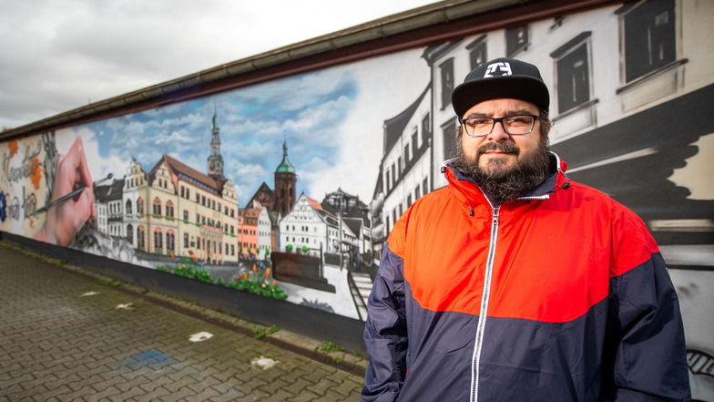 Künstler René Donath steht vor seinem neuen Wandbild am Bahnhof Pirna.