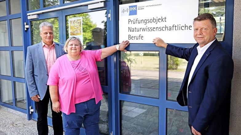 Sabine Meißner und ASG-Niederlassungsleiter Matthias Scheidig (rechts) halten gemeinsam das Schild, das IHK-Geschäftsführer Torsten Köhler mitgebracht hat, an das Eingangsportal der Nünchritzer Ausbildungsstätte.